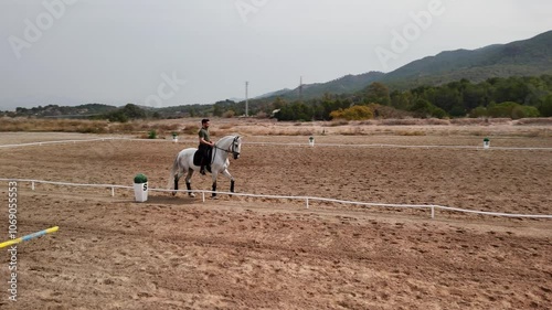 rotary drone flight over a rider training with his horse on a track.