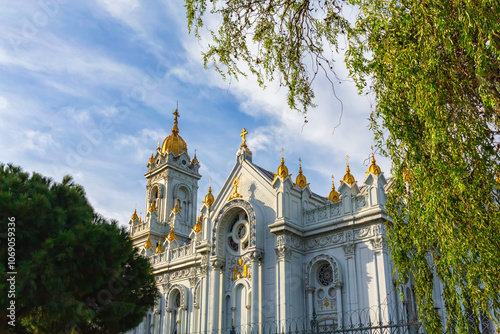 Bulgarian Iron Church, adorned with golden domes and intricate details, framed by lush trees and a bright sky. Istanbul, Turkey (Turkiye) photo