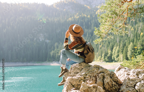 Female traveler enjoying the view of Lake among mountains. Hiking with backpack. Active lifestyle.