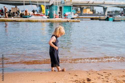 Little child girl on the City shore on the sea with a beach. Saint Petersburg, Russia - 26 July 2024 photo