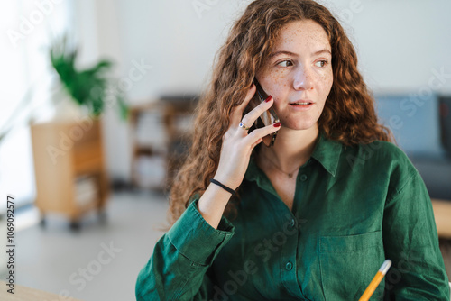 Young woman having a phone conversation in a cozy home office setting photo