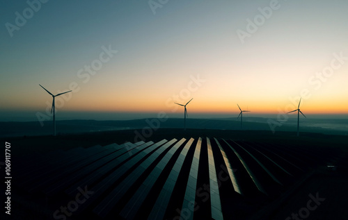 Windmill turbines generating green energy electric.Solar panels park and wind turbines at sunset.Green energy reduce carbon emissions and makes earth cleaner and more ecological.