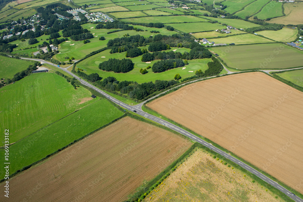 Elevated view of road going through countryside with golf course in background