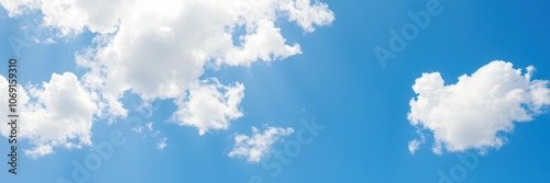 Fluffy white clouds floating in a bright blue summer sky, outdoors, clouds