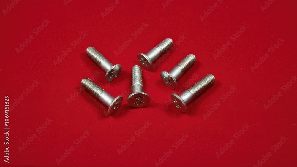 Screws and bolts for furniture repair. Seven metal bolts aligned on a vivid red surface, showcasing their shiny finish and threads. Perfect for construction projects. Screws and bolts for furniture repair. Seven metal bolts aligned on a vivid red surface, showcasing their shiny finish and threads. Perfect for construction projects.
