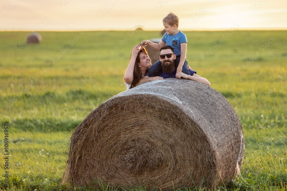 A portrait of a happy family in the fields of the Lithuanian countryside near a hay bale A portrait of a happy family in the fields of the Lithuanian countryside near a hay bale