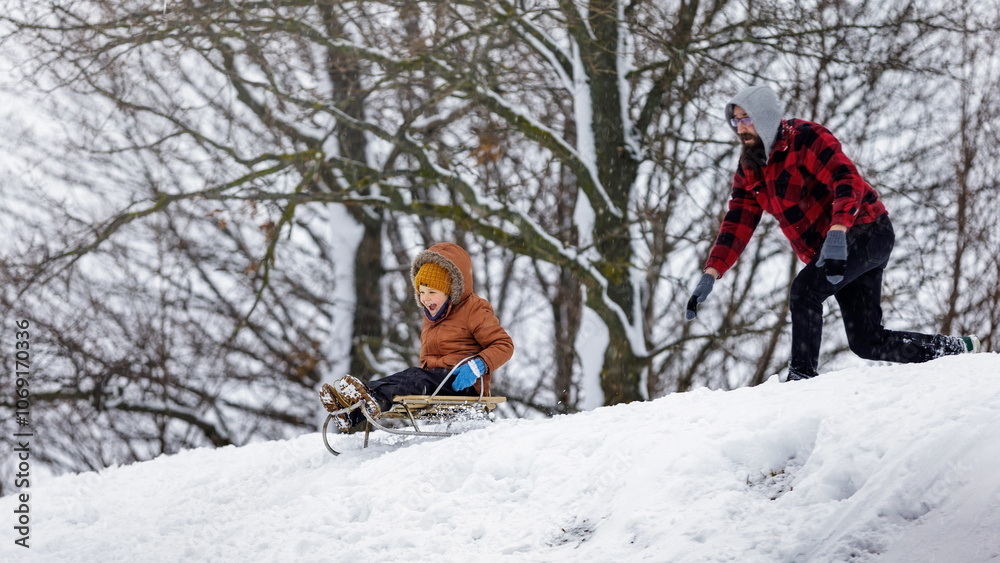 Happy family having fun sledding outdoors on the mountain in winter. father and son games. Rejoicing happy child Happy family having fun sledding outdoors on the mountain in winter. father and son games. Rejoicing happy child