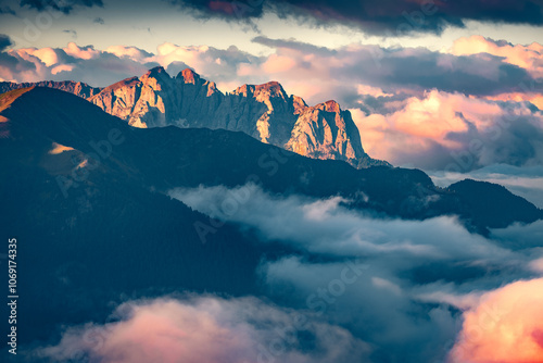 Exciting sunrise on Val di Fassa valley under huge fog. Impressive summer view from the top of Sella pass in Dolomite Alps, Italy, Europe. Beauty of nature concept background..