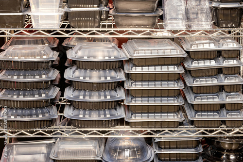 Organized stacks of transparent and opaque food storage containers in a commercial kitchen setting