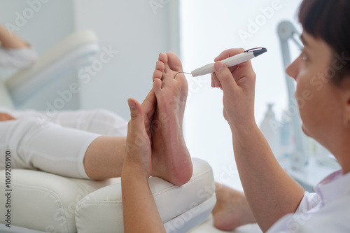 A podologist checks the diabetic  foot  with a Diabetic Foot Probe. Patient on medical pedicure procedure, visiting podiatrist. Peeling feet. Foot treatment in SPA salon.Podiatry