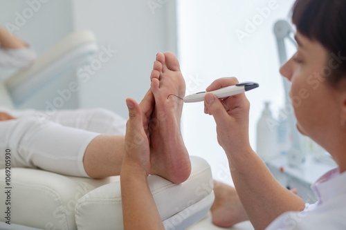 A podologist checks the diabetic  foot  with a Diabetic Foot Probe. Patient on medical pedicure procedure, visiting podiatrist. Peeling feet. Foot treatment in SPA salon.Podiatry