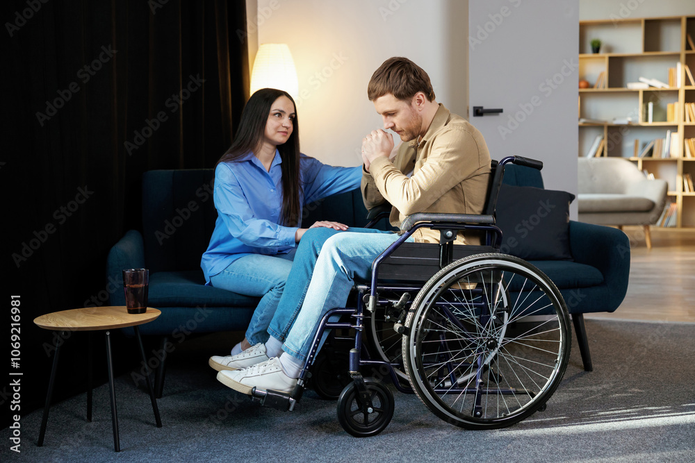 Young man in a wheelchair. Girlfriend comforting her sad boyfriend Young man in a wheelchair. Girlfriend comforting her sad boyfriend