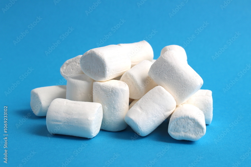 A pile of white marshmallows lies on a blue background. A pile of white marshmallows lies on a blue background.