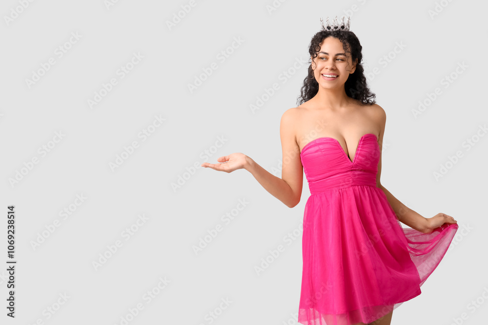 Beautiful young African-American woman in stylish pink prom dress and tiara on grey background Beautiful young African-American woman in stylish pink prom dress and tiara on grey background