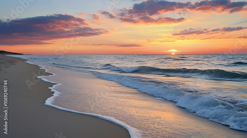 Serene beach at sunset, featuring gentle waves lapping against soft sand, and a sky painted with vibrant colors of orange, pink, and purple photo