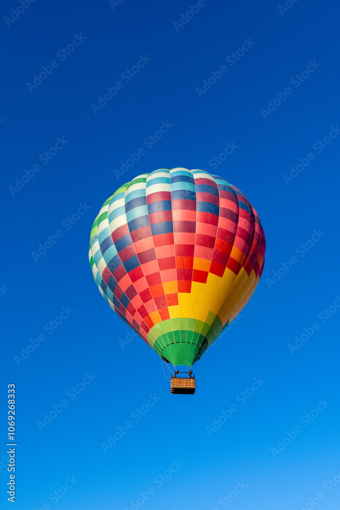 Fototapeta premium Kubicek Balloons Hot Air Balloon Soaring in Clear Blue Sky