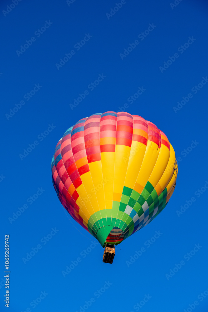 Fototapeta premium Vibrant Kubicek Hot Air Balloon Soaring in Clear Blue Sky