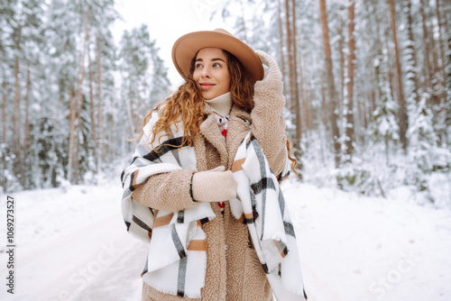 Happy woman among snowy trees in winter forest. Concept of walking, fun. Fashion style. photo