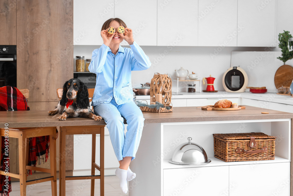 Funny little boy with muffins and cute cocker spaniel sitting on table in kitchen Funny little boy with muffins and cute cocker spaniel sitting on table in kitchen