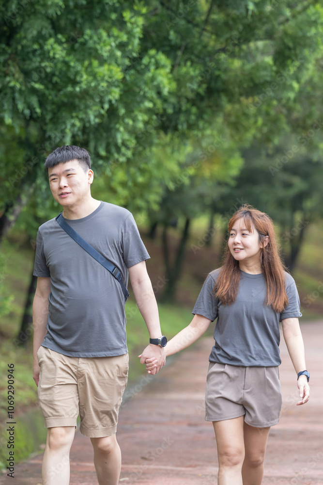 A Chinese-Malaysian couple in their 30s walk together in a green park with abundant water in Kuala Lumpur, Malaysia, on a sunny day in June 2024. A Chinese-Malaysian couple in their 30s walk together in a green park with abundant water in Kuala Lumpur, Malaysia, on a sunny day in June 2024.