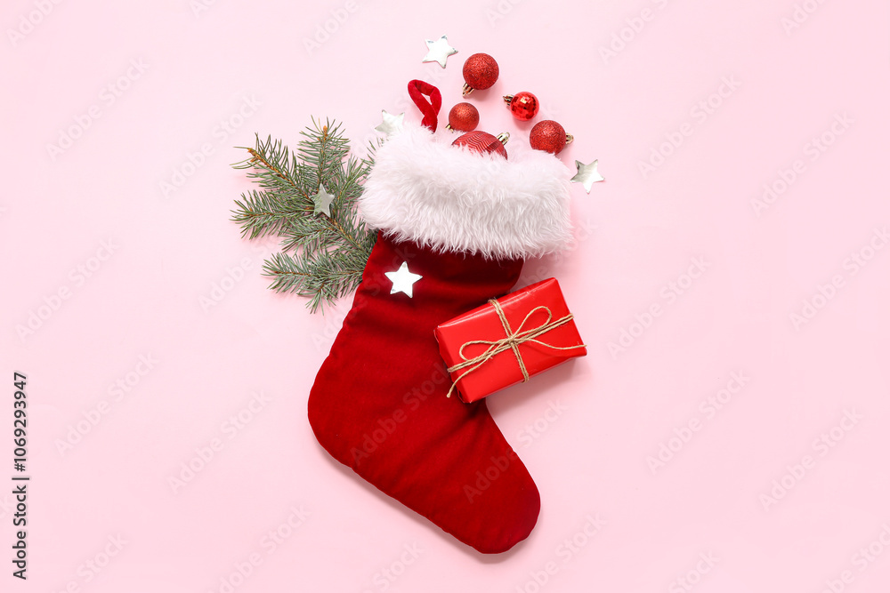 Obraz premium Christmas sock with gift and decor on pink background. Top view