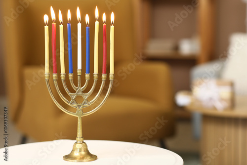 Menorah with burning candles on table at home, closeup. Hanukkah celebration photo