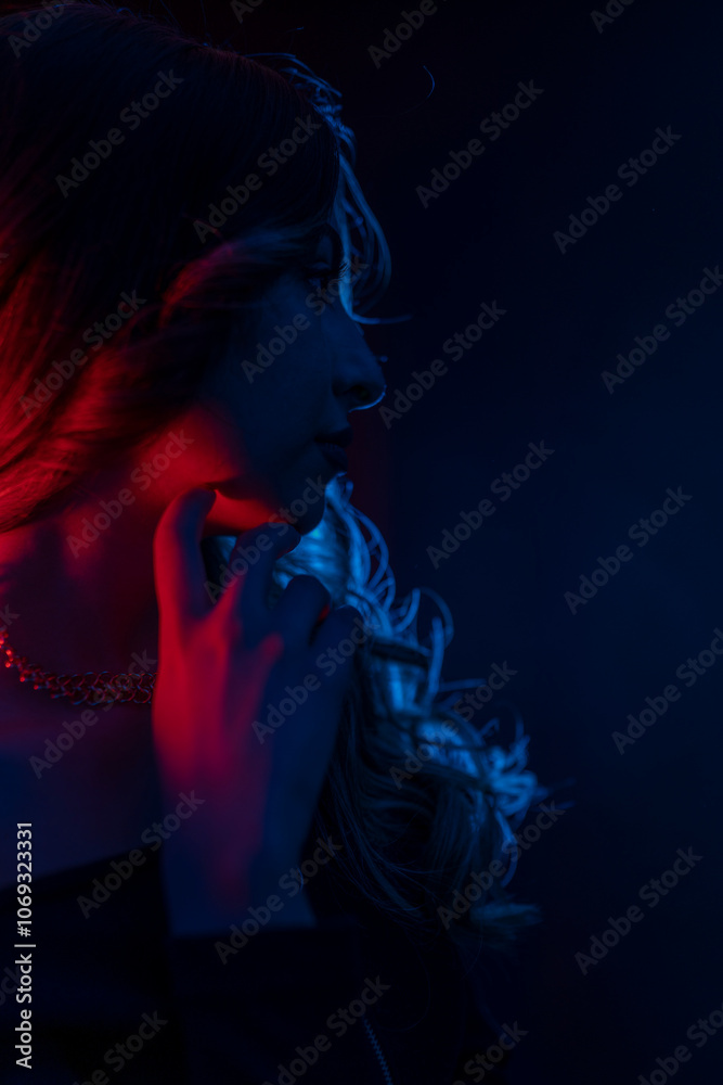 Portrait of a mysterious silhouette of a young woman standing on a blue glowing background Portrait of a mysterious silhouette of a young woman standing on a blue glowing background