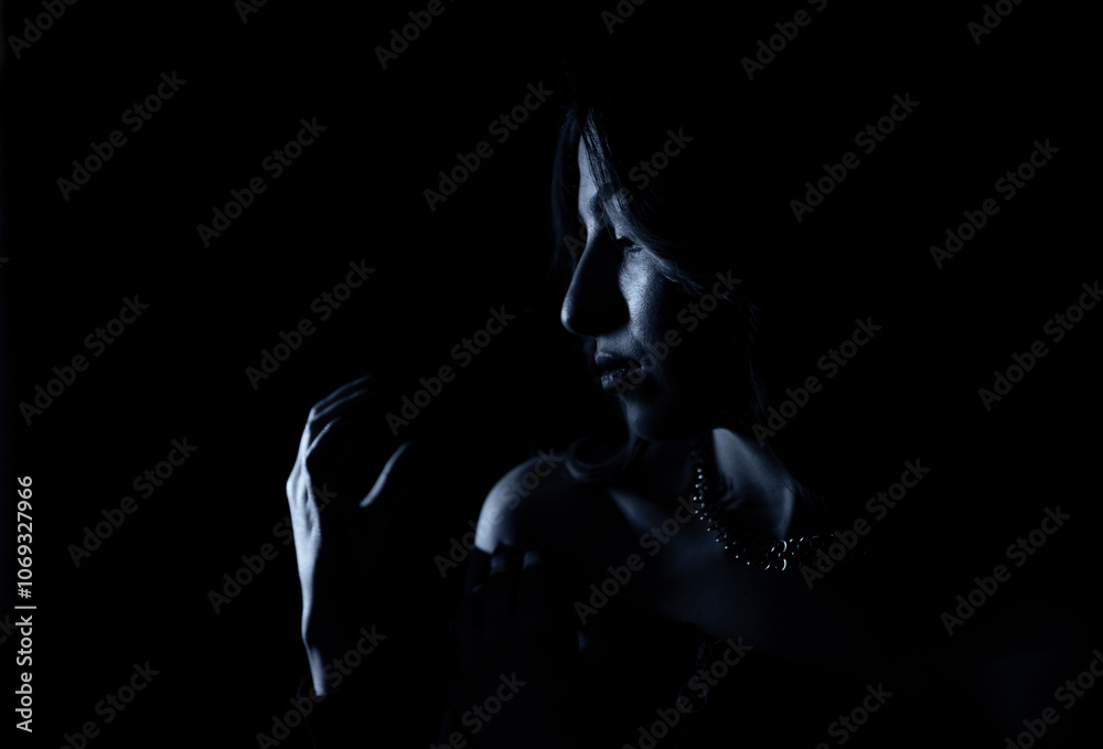 Naklejka premium Portrait of a mysterious silhouette of a young woman standing on a blue glowing background