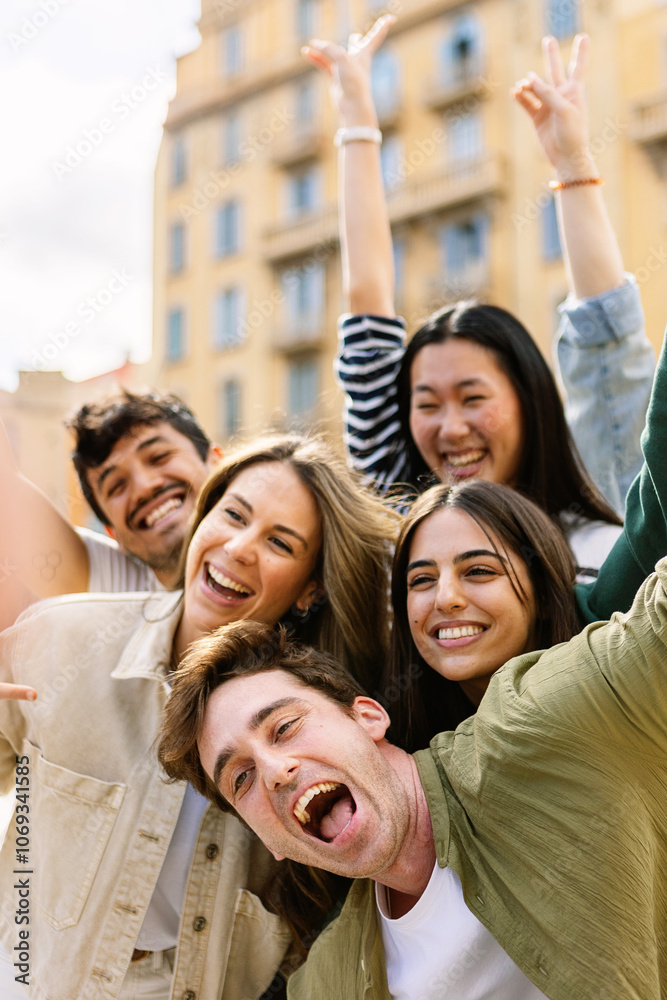 Obraz premium Vertical shot of young group of happy people enjoying time together at city street. Millennial generation friends having fun, laughing while enjoying holiday trip. Friendship and youth concept