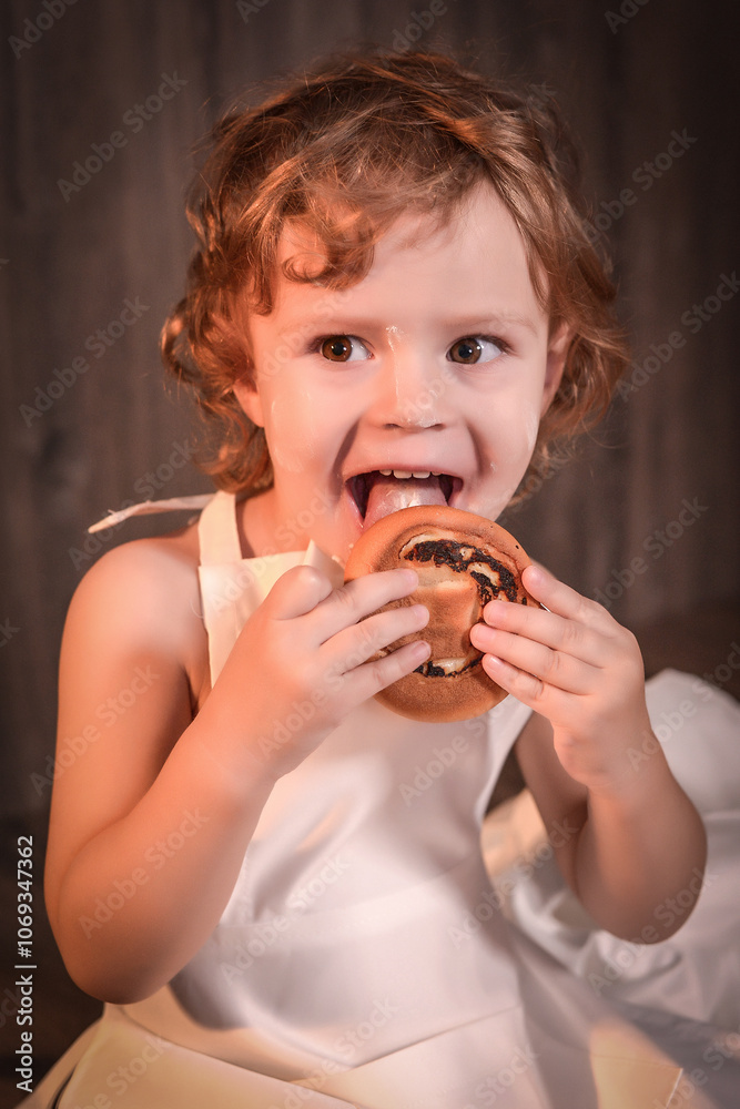 The photo shows a smiling child enthusiastically eating fresh baked goods with filling. The photo shows a smiling child enthusiastically eating fresh baked goods with filling.