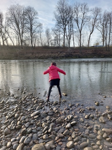Girl balancing on stones at riverbank
