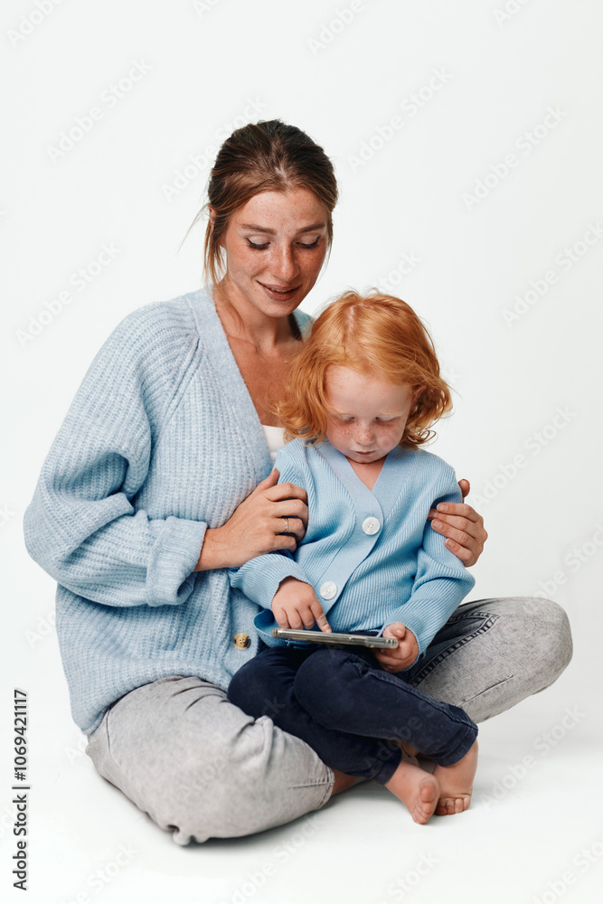 Mother and daughter engaged in digital learning together with a tablet on the floor Mother and daughter engaged in digital learning together with a tablet on the floor