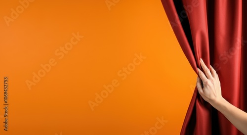 Obraz na płótnie Hand pulls back red curtain, revealing orange background