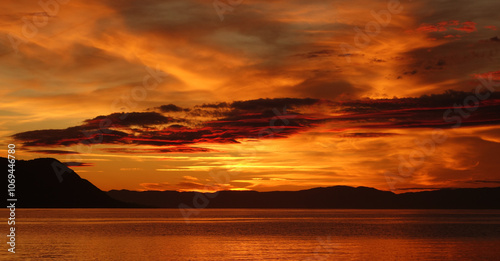 Fiery Sunset Over Calm Waters with Dramatic Cloudscape