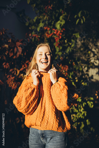 Woman in a cozy orange sweater embracing autumn vibes photo