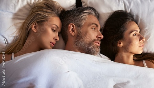 A man sleeping with two women in his bed, polyamorous relationship