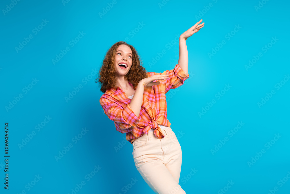 Joyful young woman in casual attire gesturing happily against a bright blue background Joyful young woman in casual attire gesturing happily against a bright blue background