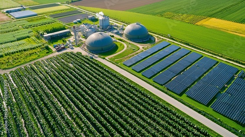 Overview of a biogas production facility with adjacent farmland and solar panels, showcasing diversified renewable energy. 8K