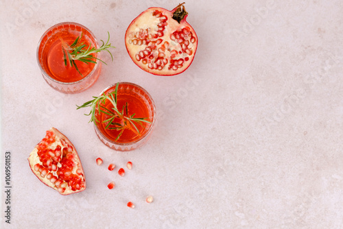 Refreshing pomegranate drinks garnished with fresh herbs on a light marble surface. top view. space for text photo