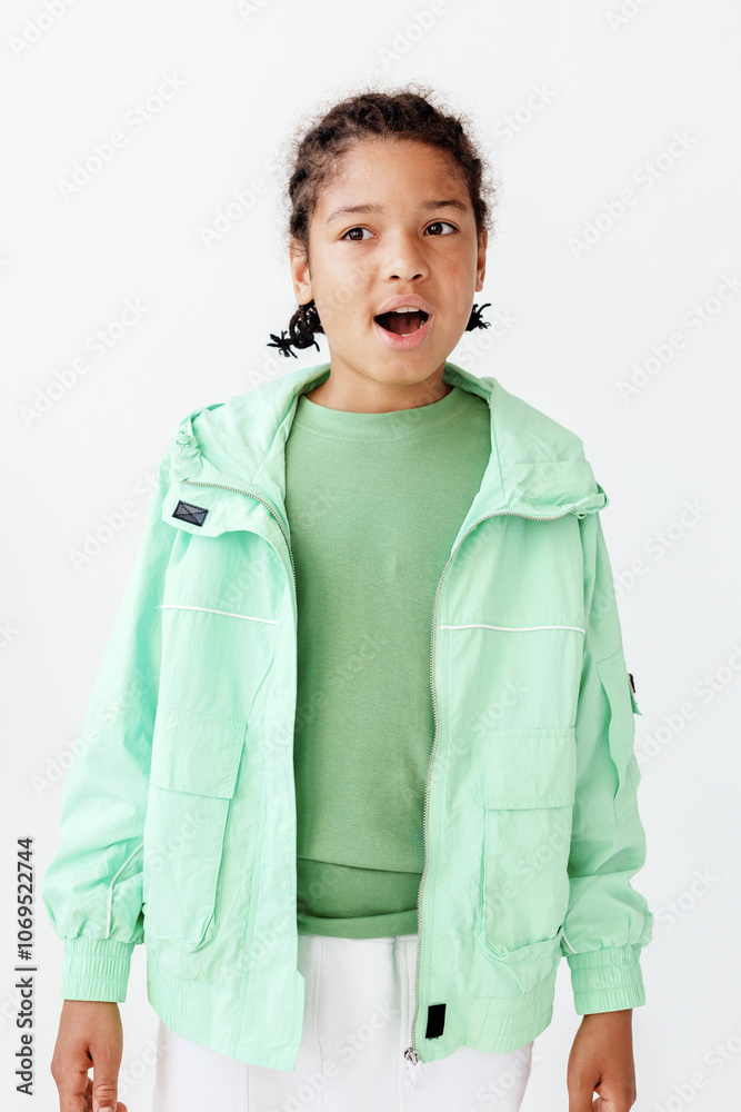 Excited young boy in stylish green jacket and white pants against clean white backdrop Excited young boy in stylish green jacket and white pants against clean white backdrop