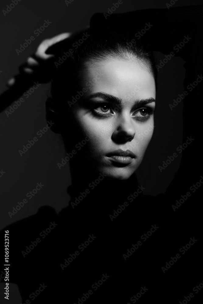 Thoughtful woman in black attire, captured in dramatic lighting with striking shadows. Portrait emphasizing emotion and strong facial features. Thoughtful woman in black attire, captured in dramatic lighting with striking shadows. Portrait emphasizing emotion and strong facial features.