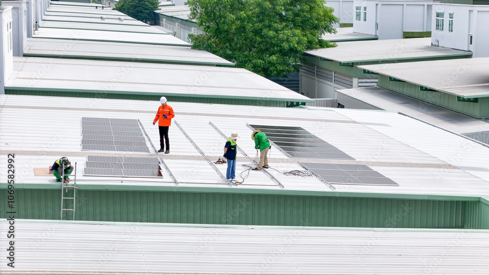 Obraz premium Aerial view of a rooftop with solar panels, showing a technician in safety gear performing maintenance. The scene highlights renewable energy, solar technology, and sustainable infrastructure.