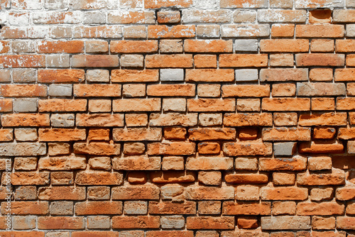 Red shabby grungy brick wall. Free space for an inscription. Can be used as a background or poster. Fragment of an old brick wall with bumps and textured plaster. 