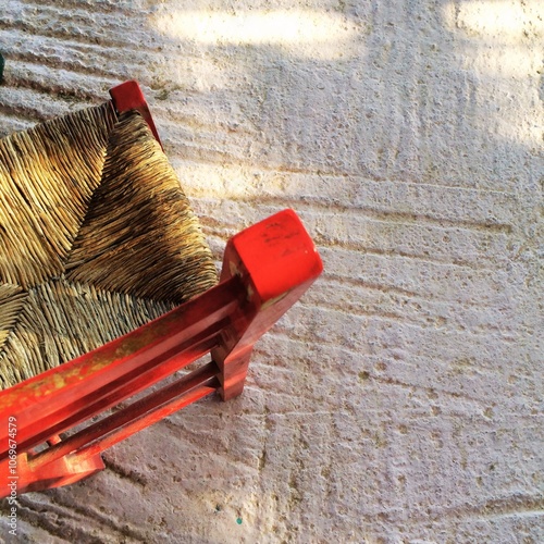 Title: Rustic Red Wooden Chair with Woven Seat on Textured Floor, Top View
 photo