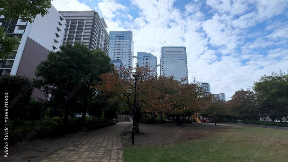A quiet urban park in Tokyo with autumn trees, modern skyscrapers, and a children's playground