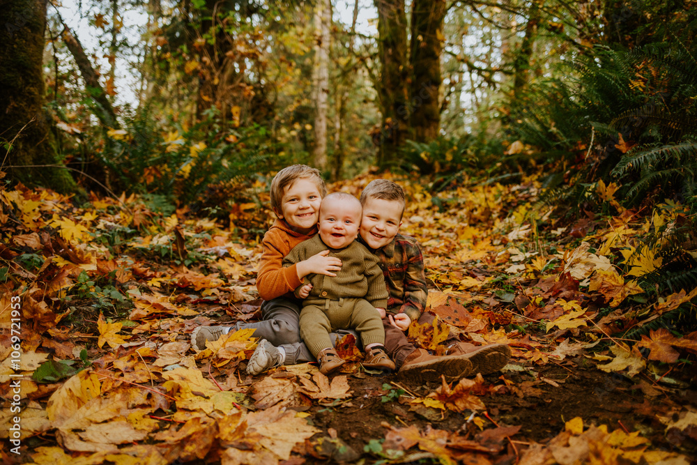 Little boys sitting in the colorful fall leaves in the northwest.