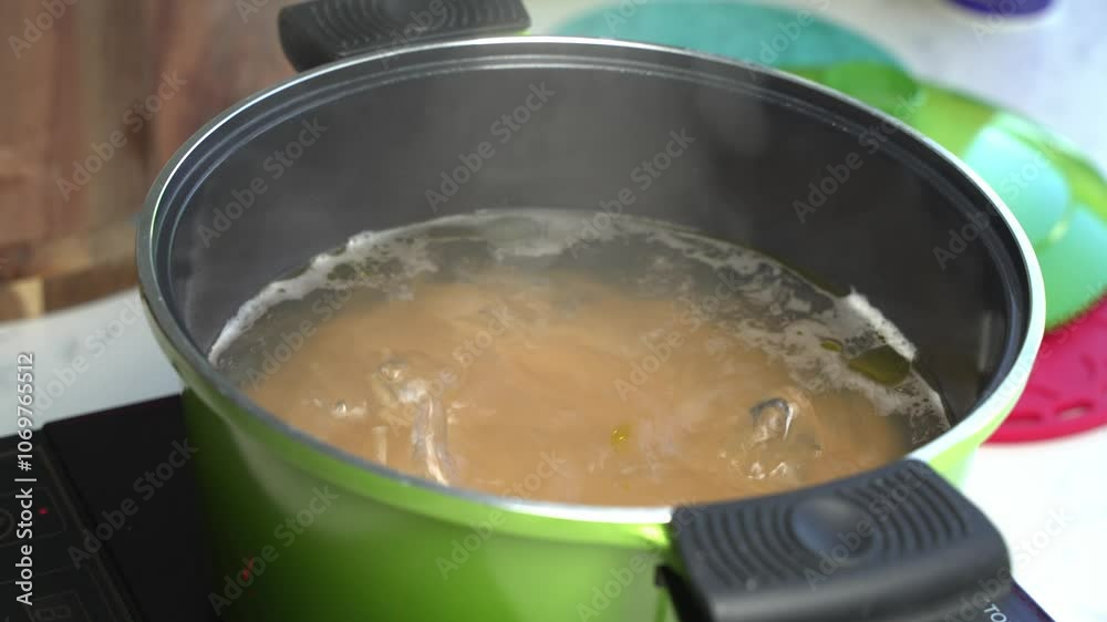 Hot spaghetti lifted with tongs from boiling water, checking the cooked pasta, close up Hot spaghetti lifted with tongs from boiling water, checking the cooked pasta, close up