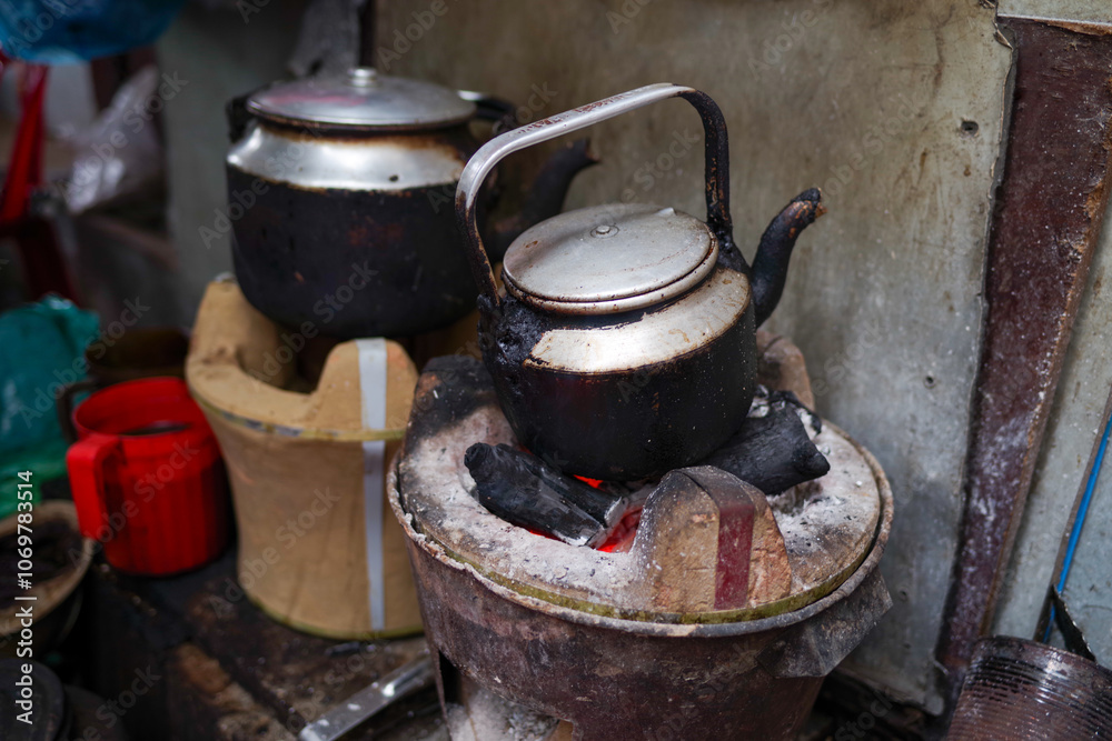 Metal kettles simmer over a glowing charcoal stove on a bustling urban street Metal kettles simmer over a glowing charcoal stove on a bustling urban street