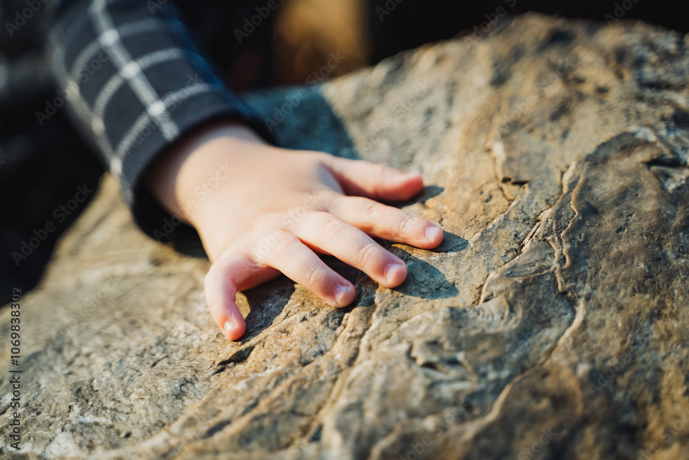 Φωτογραφία A young childs small hand is gently touching the surface of a very large rock, f