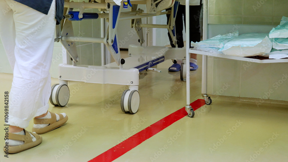 Fototapeta premium Two healthcare providers rush a gurney through a hospital operating room, emphasizing the critical nature of patient care in surgical settings
